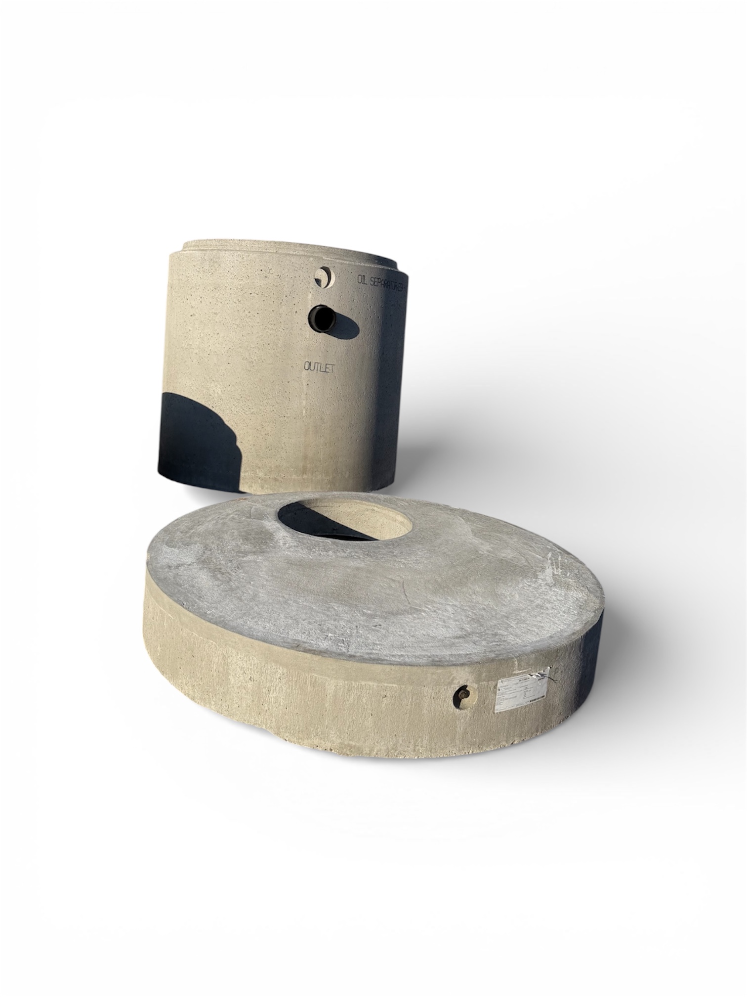 Två stora prefabricerade betongelement - en cylindrisk stigbrunn och en platt rund täckplatta - visas på en vit bakgrund, perfekt för Oljeavskiljare betong 10 l/ sekunden - kompletta paketlösningar.