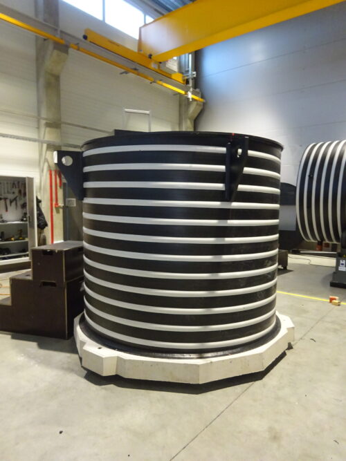 Lagringstank ID dubbelväggig är en stor cylindrisk svart lagringstank med horisontella vita ränder, belägen i en industriell lagerlokal med betonggolv, högt i tak och en gul traverskran ovanför.