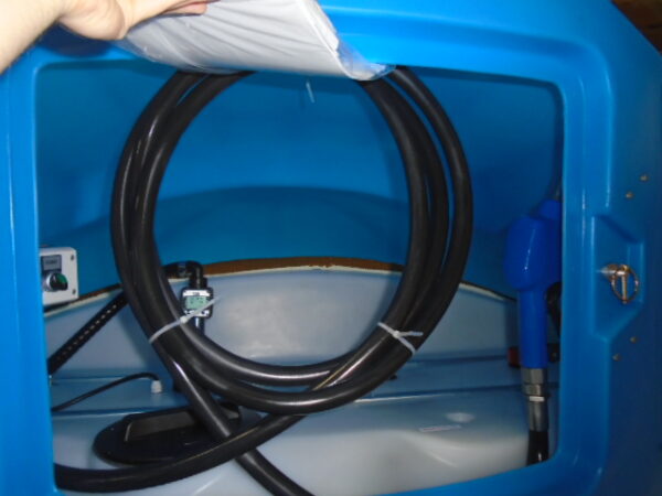 En hand öppnar locket till en DESO AdBlue-tank på 5000 liter och avslöjar svarta slangar, ett blått munstycke och en liten kontrollpanel inuti.