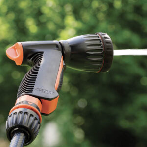 Närbild av Claber "MULTI-JET" strålpistol i svart och orange som sprutar vatten, med en suddig bakgrund av gröna bladverk.