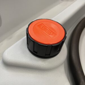 Närbild av ett svart och orange Tanklock Cemo DT-Mobil Easy 2" Endast Lock-lock märkt GEKO på en vit gjuten yta, möjligen en tank eller behållare, med en svart slang till höger.