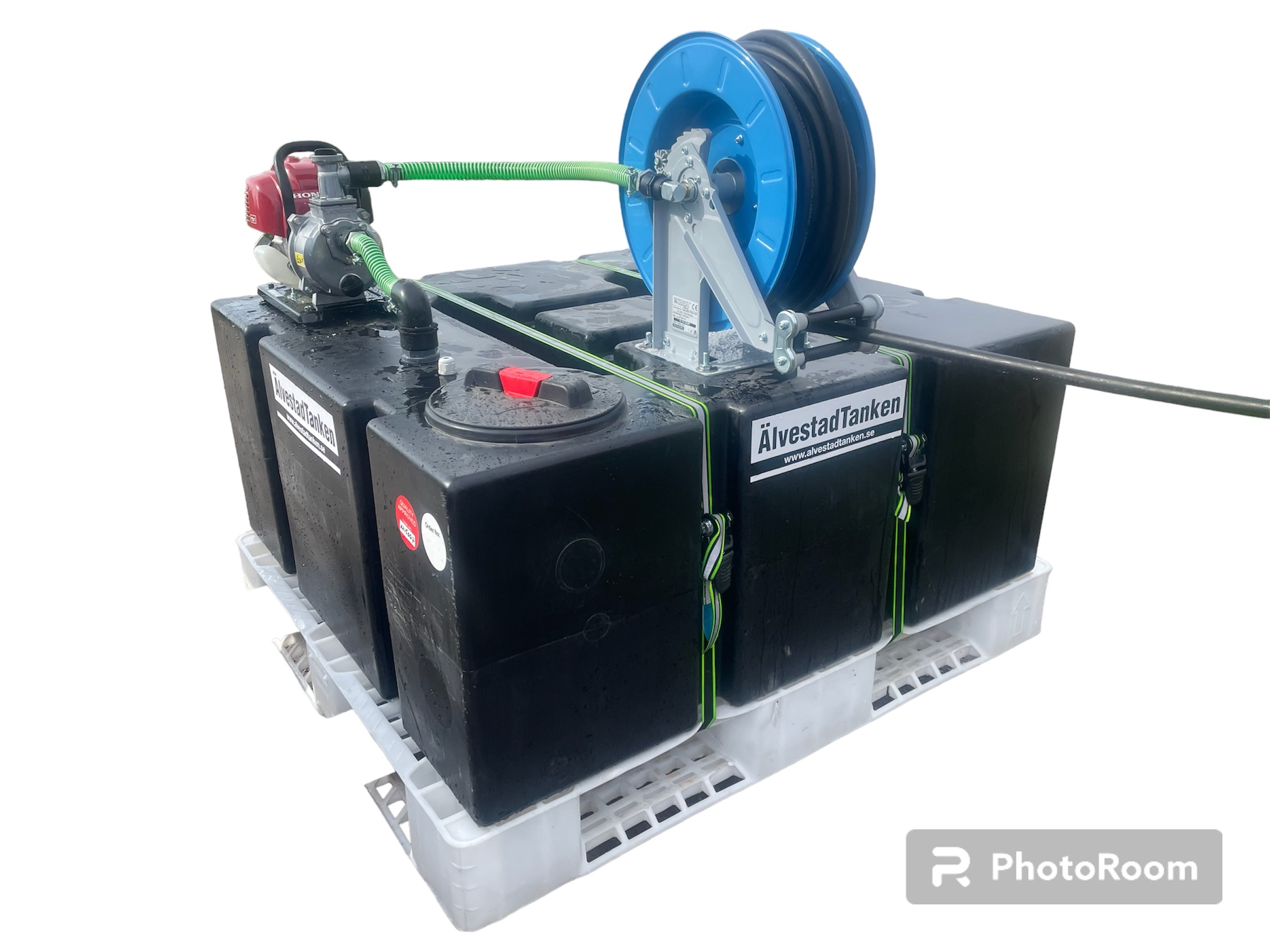 En portabel bränsleförvaringsenhet med tre stora svarta tankar, en slangvinda med grön slang och en röd motor, monterad på en vit plastpall. Tankarna är märkta "ÄlvestadTanken.".