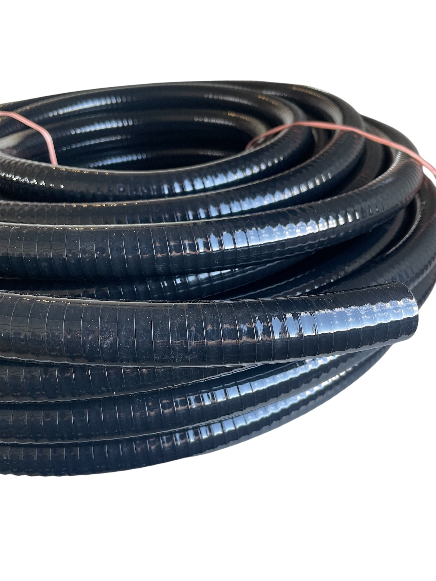 En närbild av ett svart Sugslang PVC d20 för diesel/olja/vatten flexibelt rör med räfflad yta, vilande på en vit bakgrund. En tunn röd kabel syns löpa vid sidan av kabelröret.